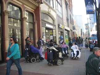 Busy Market St. in Philadlephia with wheelchair artists in the sidewalk traffic.