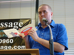  Owen at a microphone holding up an open book